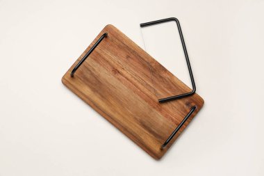 Açık arkaplanda peynir dilimleyicisi olan ahşap mutfak tahtası