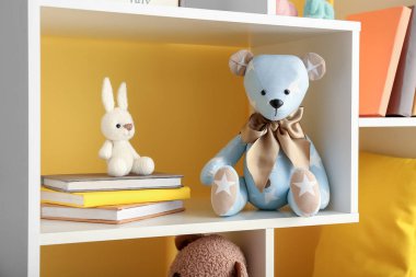 Oyuncak ayı ve tavşan kitaplarla sarı duvarın yanında
