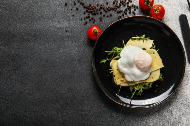 Arkaplanda lezzetli bir Benedict yumurtası tabağı.