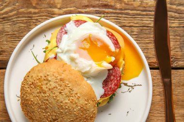 Ahşap arka planda lezzetli yumurta Benedict tabağı, yakın plan.