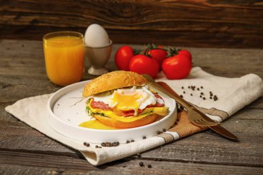 Lezzetli yumurtalı Benedict ve ahşap arka planda bir bardak portakal suyu.