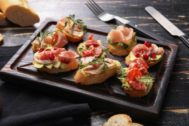 Koyu ahşap arka planda jambonlu lezzetli bruschettalar.