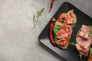 Lezzetli bruschetta tabağı, arka planda jambon, yakın plan.