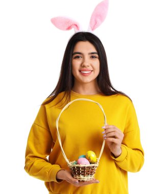 Beyaz arka planda Paskalya yumurtası sepeti olan tavşan kulaklı genç bir kadın.