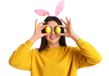 Beyaz arka planda Paskalya yumurtaları olan tavşan kulaklı genç bir kadın.