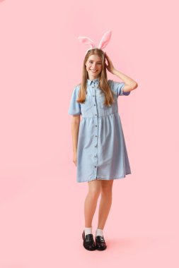 Pembe arka planda tavşan kulaklı genç bir kadın. Paskalya kutlaması