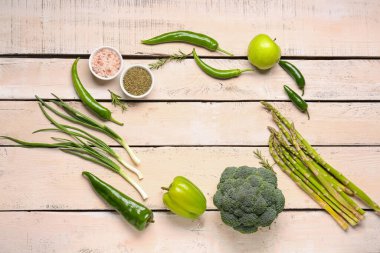 Beyaz ahşap arka planda farklı yeşil sebzelerden yapılmış çerçeve