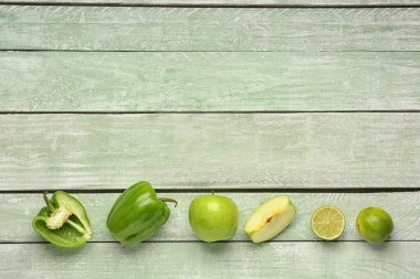 Renkli ahşap arka planda yeşil biber, elma ve limon kompozisyonu