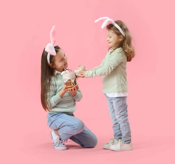 小さな女の子でウサギの耳とともにイースターケーキオンピンクの背景 — ストック写真