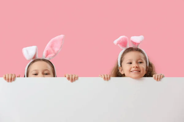 ピンクの背景に空白のポスターを持つウサギの耳の小さな女の子 イースターのお祝い — ストック写真
