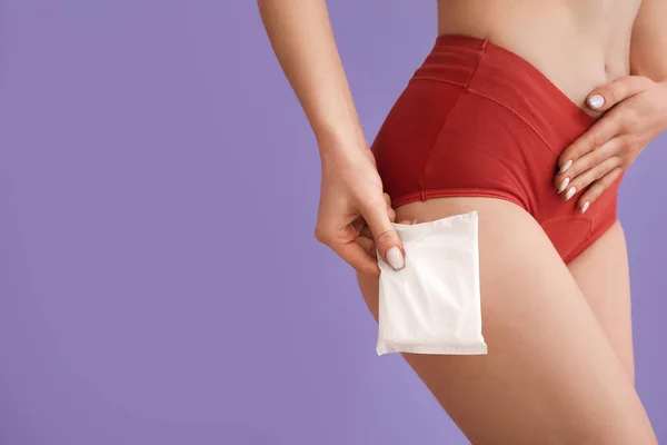 Young woman in menstrual panties with pad on lilac background, closeup
