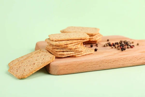 Board Tasty Crackers Peppercorn Green Background — Stock Photo, Image