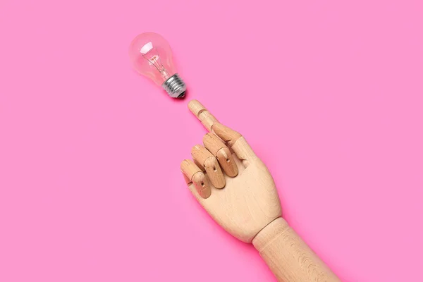Wooden hand with light bulb on pink background. Insight concept