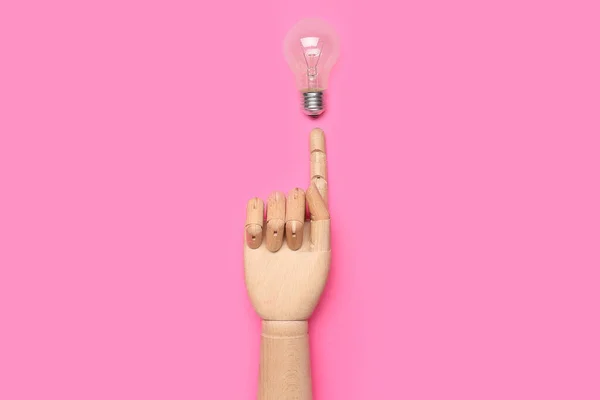 Wooden hand with light bulb on pink background. Insight concept