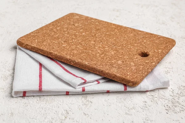 Cork kitchen board and napkin on light background