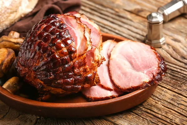 Plate with tasty smoked ham on wooden background
