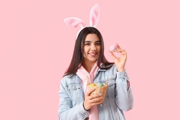 Mladá Žena Králičí Uši Košíkem Velikonočních Vajec Růžovém Pozadí — Stock fotografie