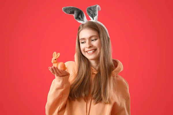 若いです女性でウサギ耳とともにイースターウサギオン赤背景 — ストック写真