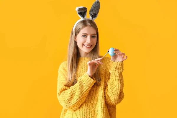 Tavşan Kulaklı Genç Kadın Sarı Arka Planda Paskalya Yumurtası Boyuyor — Stok fotoğraf