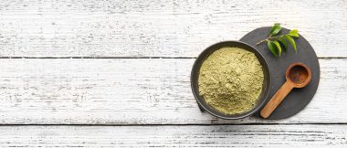 Pudralanmış kibrit çayı ve hafif ahşap arka planda metin için yeri olan kepçe ile kase