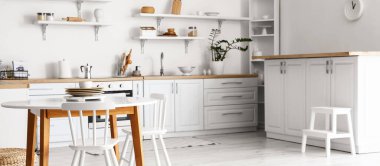 Stylish interior of light kitchen with dining table