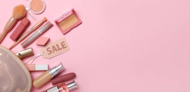 Makyaj malzemesi ve satılık aksesuarlarla dolu çanta pembe arka planda metin için yer var