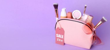 Makyaj malzemelerini ve satılık aksesuarları olan çanta, metin için alanı olan leylak arkaplan