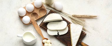 Farklı taze süt ürünleri ve arka planda tavuk yumurtaları.