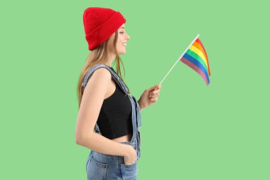 Beautiful young woman with LGBT flag on green background
