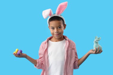 Mavi arka planda Paskalya yumurtası ve tavşanı olan küçük Afro-Amerikalı çocuk.
