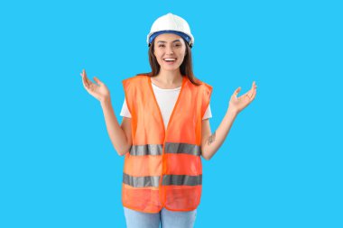 Mavi arka planda yelek giyen kadın işçi.