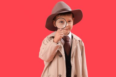 Cute little detective with magnifier on red background