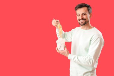 Handsome man with box of Chinese noodles on red background