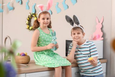 Oyuncak tavşanlı küçük çocuklar ve mutfakta paskalya yumurtası.
