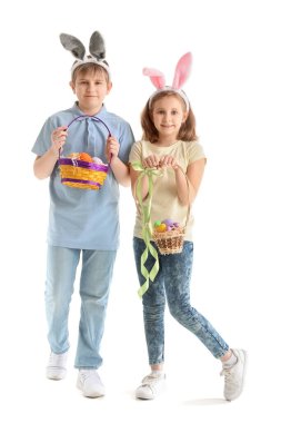 Beyaz arka planda Paskalya yumurtası dolu sepetleri olan tavşan kulaklı küçük çocuklar.