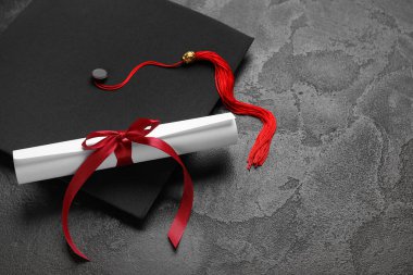 Diploması kırmızı kurdeleli ve siyah şapkalı.