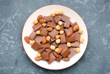 Lezzetli çikolata ve fındıklı tabak mavi arka planda.