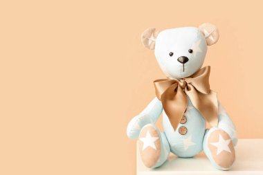 Oyuncak ayı rafta, bej duvarın yanında.