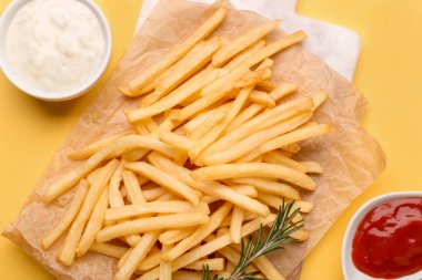 Lezzetli patates kızartması, mayonez ve sarı arka planda ketçap.