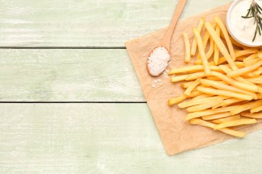 Lezzetli patates kızartması, mayonez ve yeşil ahşap arka planda tuz.