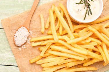Lezzetli patates kızartması, mayonez ve yeşil ahşap arka planda tuz.