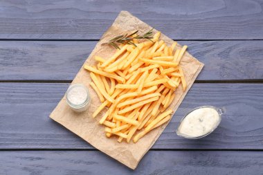 Lezzetli patates kızartması, tuz ve mayonez mavi ahşap arka planda.