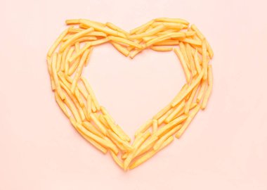 Pembe arka planda patates kızartmasından yapılmış bir kalp.