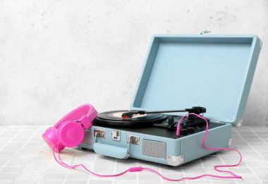 Işık duvarının yanındaki masada vinil diski ve kulaklığı olan kayıt çalar