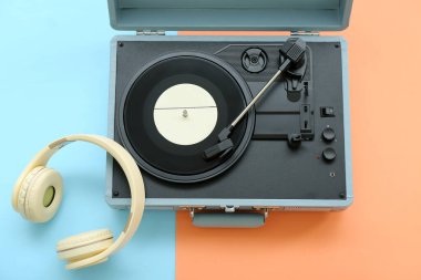Renk arkaplanında vinil diski ve kulaklığı olan kayıt çalar