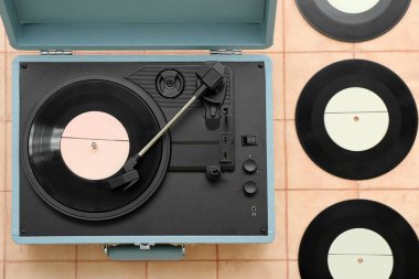 Bej kaplama üzerinde vinil diskleri olan kayıt çalar