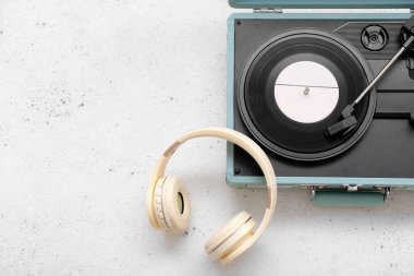 Açık arkaplanda vinil diski ve kulaklığı olan kayıt çalar