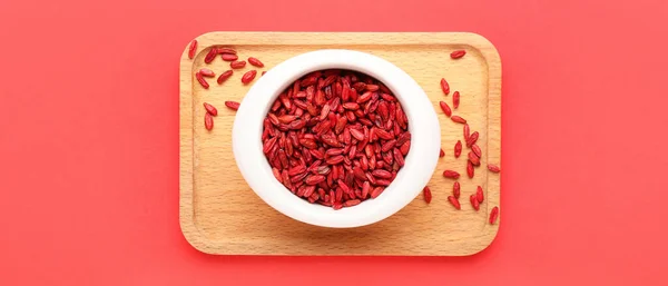 Bowl with dried barberries on red background, top view