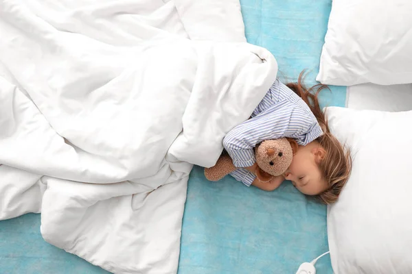 Küçük Kız Oyuncağıyla Yatak Odasındaki Elektrikli Isıtma Yastığında Uyuyor — Stok fotoğraf