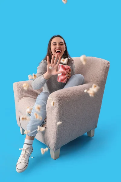 Young Woman Throwing Popcorn Soft Armchair Blue Background — Stock Photo, Image